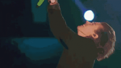 a man is singing into a microphone while holding a flashlight .