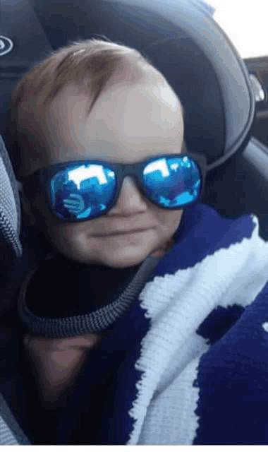 a baby wearing sunglasses and a blue blanket