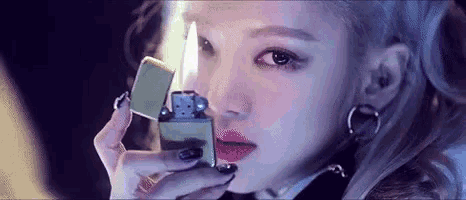 a woman is holding a zippo lighter in front of her face .