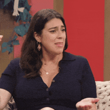a woman in a blue shirt is sitting on a couch making a funny face