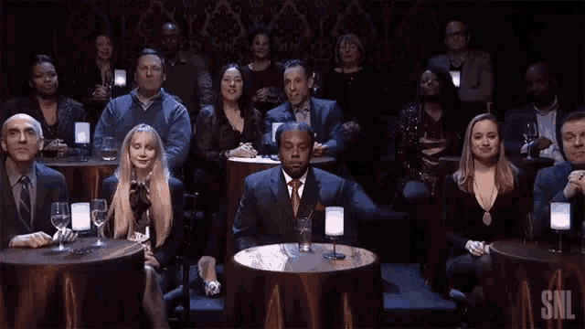 a group of people sitting at tables with snl written on the table