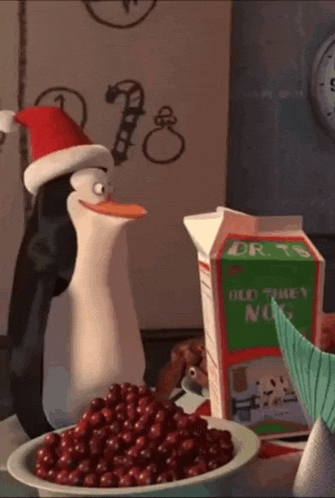 a penguin wearing a santa hat is next to a bowl of cranberries