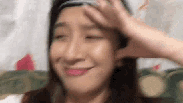 a woman is smiling and touching her forehead .