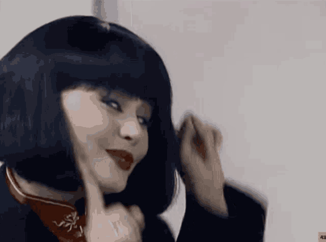 a woman wearing a black wig and red lipstick looks at the camera