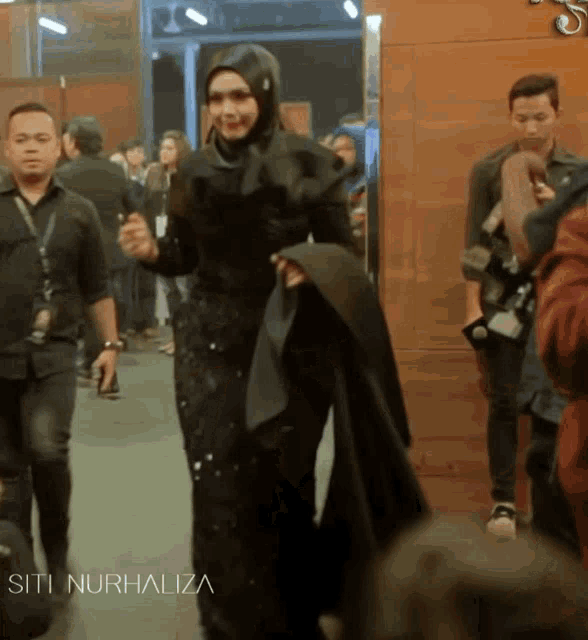 a woman in a black dress with the name siti nurhaliza written on the bottom