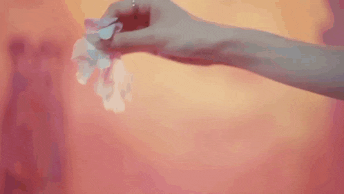 a woman in a white dress is standing in front of a pink wall .