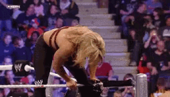 a woman is kneeling down in a wrestling ring with a wwe logo on her pants