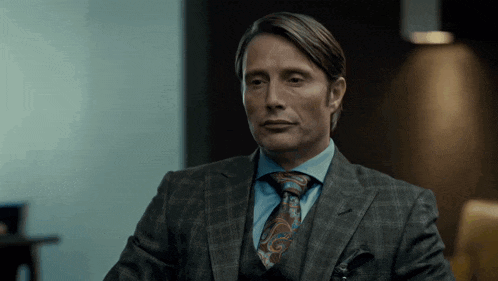 a man in a suit and tie is sitting in a room