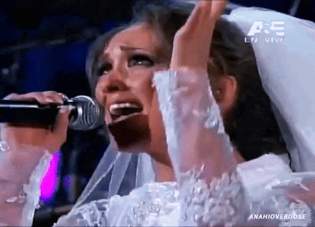 a woman in a bride 's dress singing into a microphone with a a & e logo in the background