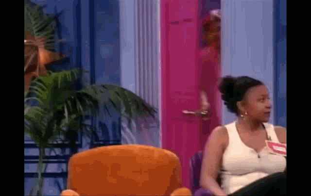 a woman is sitting in a chair in front of a pink door