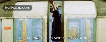 a man is hanging from a railing on a subway car .