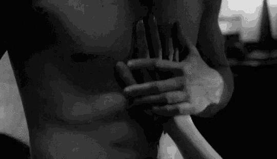a man without a shirt is being held by a woman 's hands .