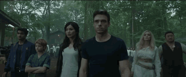a group of people are standing next to each other in the woods