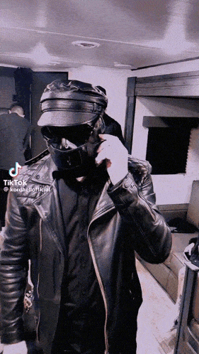 a man wearing a mask and a leather jacket has tiktok written on his face