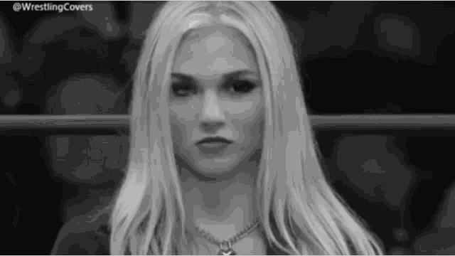 a black and white photo of a woman standing in a wrestling ring looking at the camera .