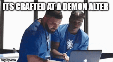 two men in blue scrubs are looking at a laptop computer with the caption `` its crafted at a demon alter '' .
