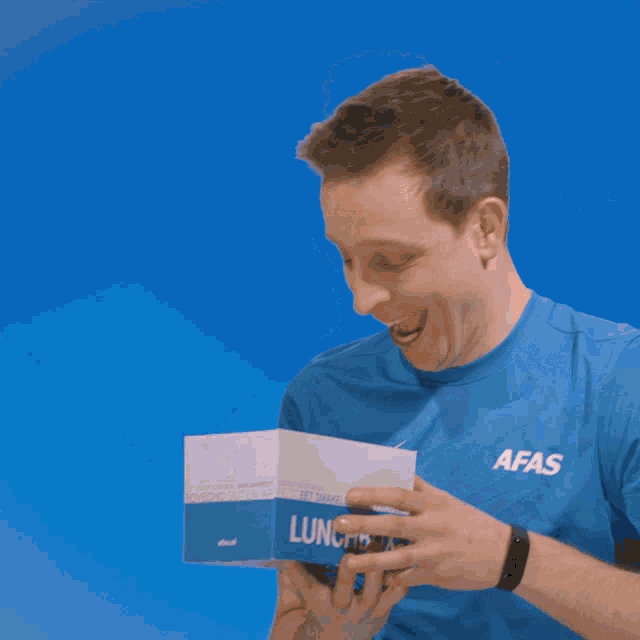 a man in a blue shirt is eating popcorn from a box that says ' microwave ' on it