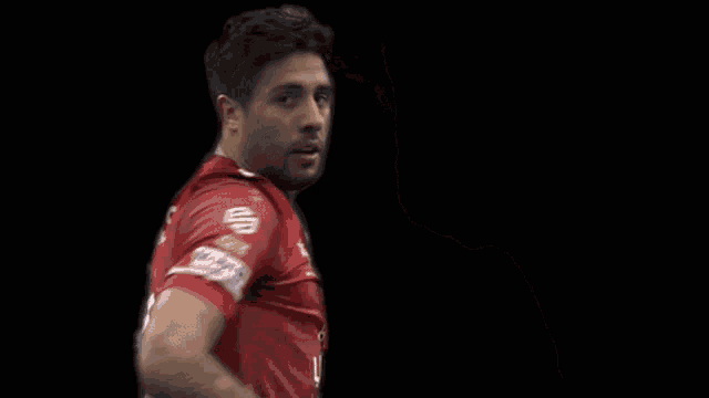 a man is wearing a red jako jersey and smiling