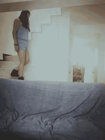 a woman in a blue dress is standing on a couch