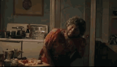 a woman in a red dress is standing in a kitchen looking at something