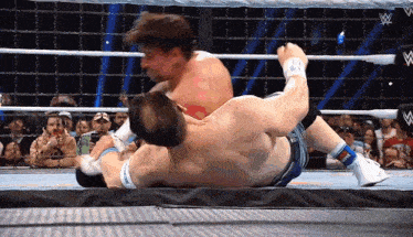 two men are wrestling in a ring with a w logo on the bottom