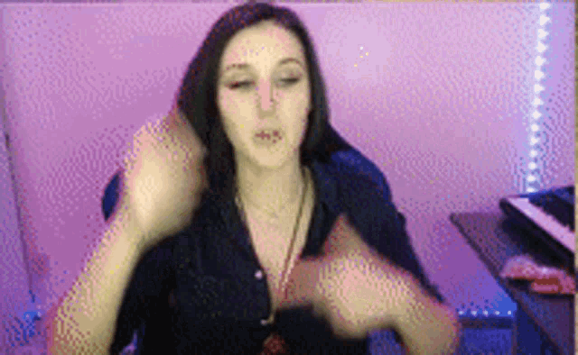 a woman is sitting in front of a keyboard in a room with purple lights on the wall .