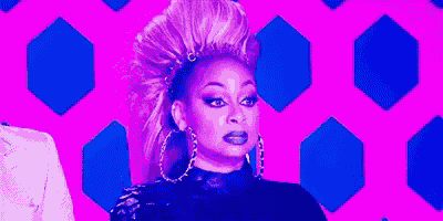 a woman with a mohawk and hoop earrings is standing in front of a pink background .