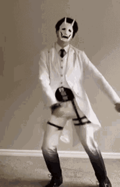 a man wearing a white suit and mask is dancing in a room .