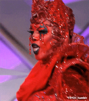 a drag queen is wearing a red dress and a red crown .