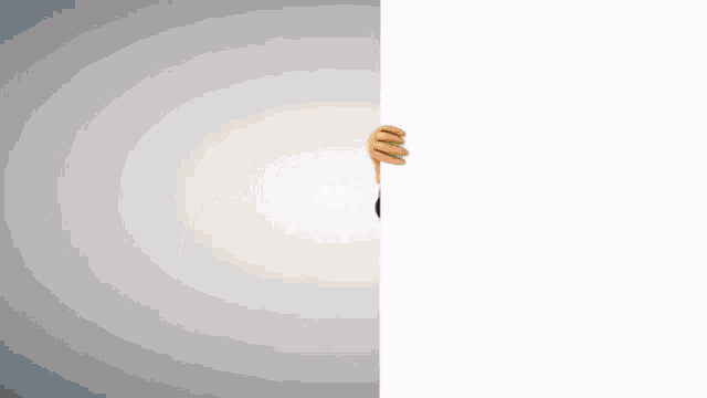 a person in a black hat is peeking over a white wall