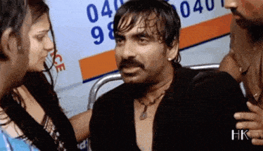 a man with a mustache is talking to a woman in front of an ambulance with numbers on it