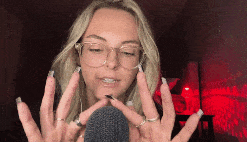 a woman with long nails and glasses is holding a microphone