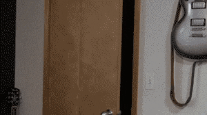 a white electric guitar is hanging on a wall next to a door .
