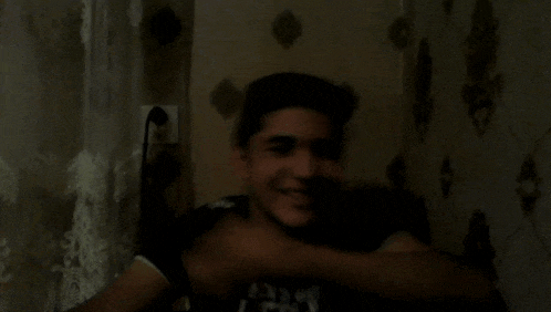 a young man wearing a shirt that says ' the north face ' on it smiles in a dark room