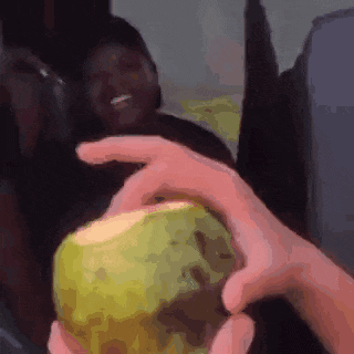a person is holding a coconut in their hand in front of a man .