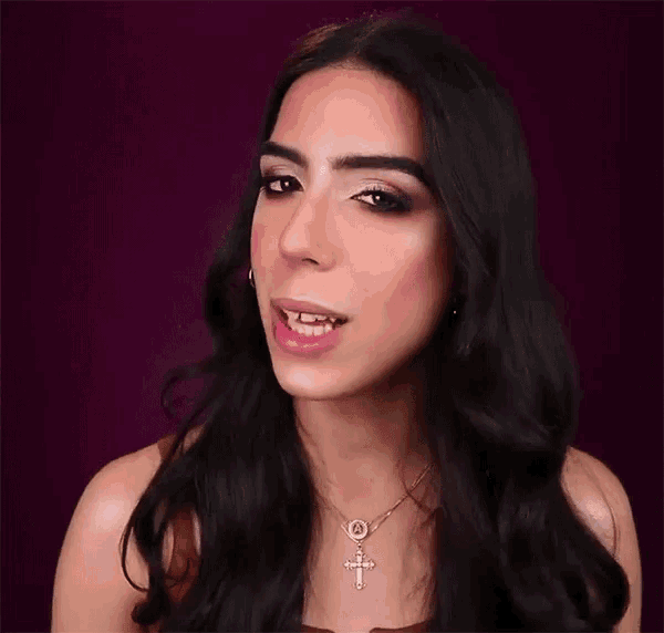 the woman is wearing a cross necklace and earrings .