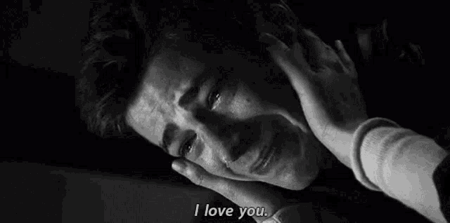 a man is crying in a black and white photo with a woman holding his head .