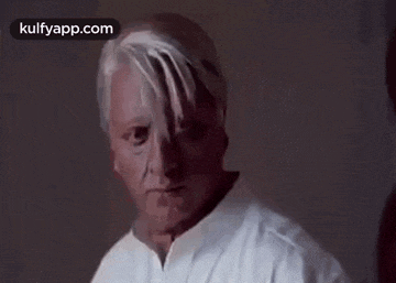 a man with blood on his face is wearing a white jacket .