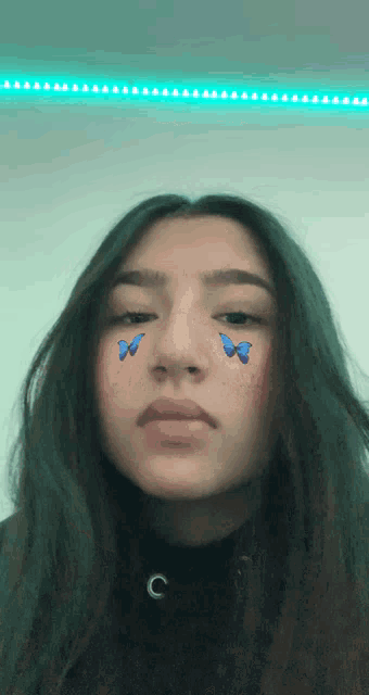 a girl with blue butterflies on her face has the letter c on her necklace