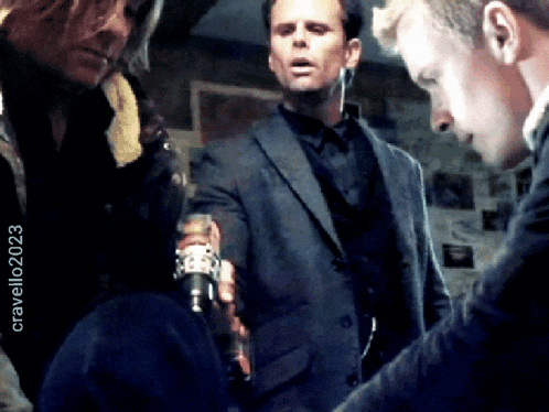 a man in a suit talks to another man in a black shirt with the year 2023 on the bottom of the image