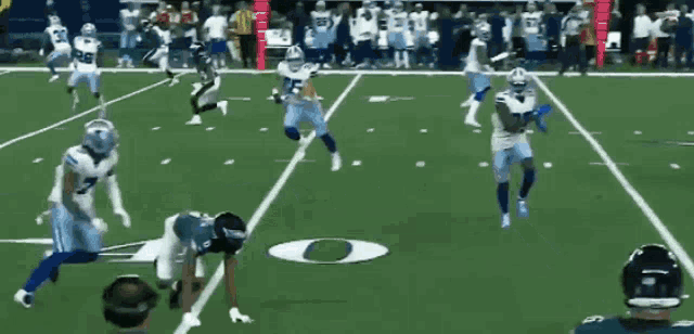 a group of football players are playing on a field with the letter o in the middle