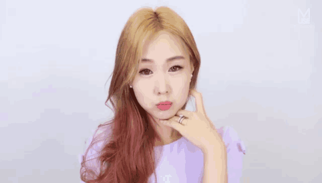a woman with a ring on her finger is wearing a pink shirt