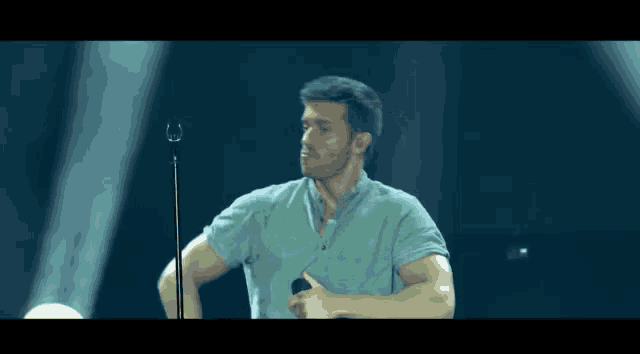 a man singing into a microphone and giving a thumbs up sign