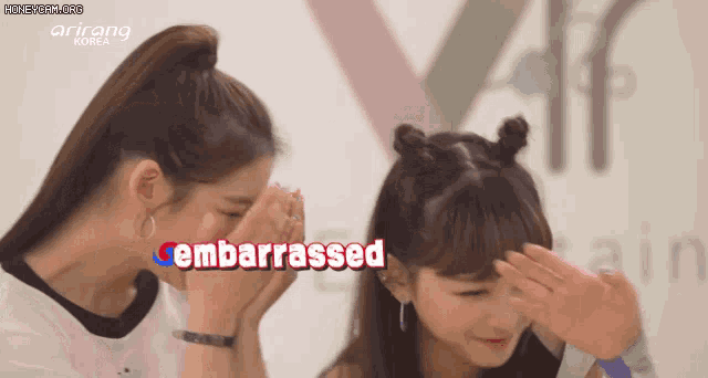 two girls covering their faces with their hands and the word embarrassed in red