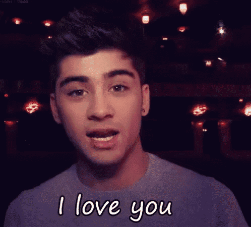 a young man is saying i love you while looking at the camera .