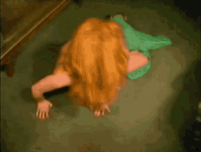 a woman with red hair crawling on the floor