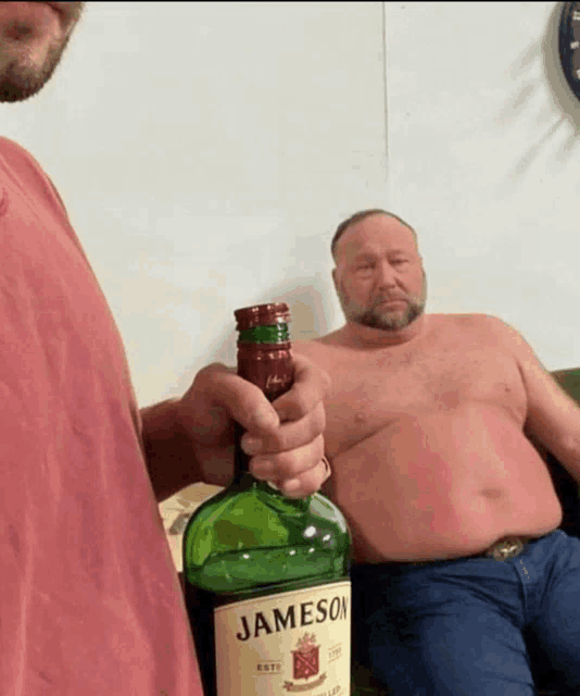 a man holding a bottle of jameson next to another shirtless man