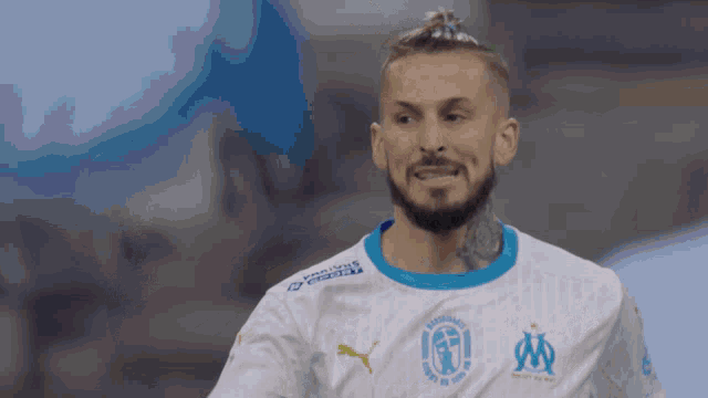 a man with a beard wears a white jersey with a blue collar