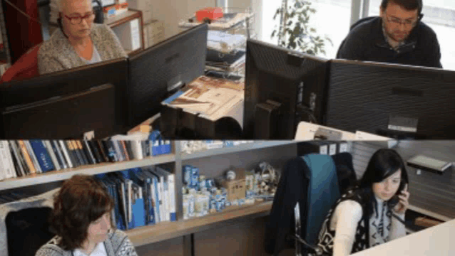 a woman talking on a cell phone while sitting at a desk in front of a computer monitor
