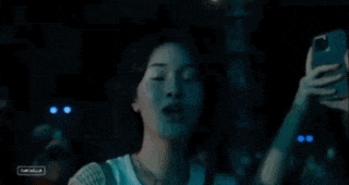 a woman is taking a selfie with a cell phone in a crowd of people .